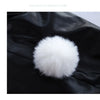 A fluffy white pom-pom decoration is placed on a piece of black faux leather fabric.
