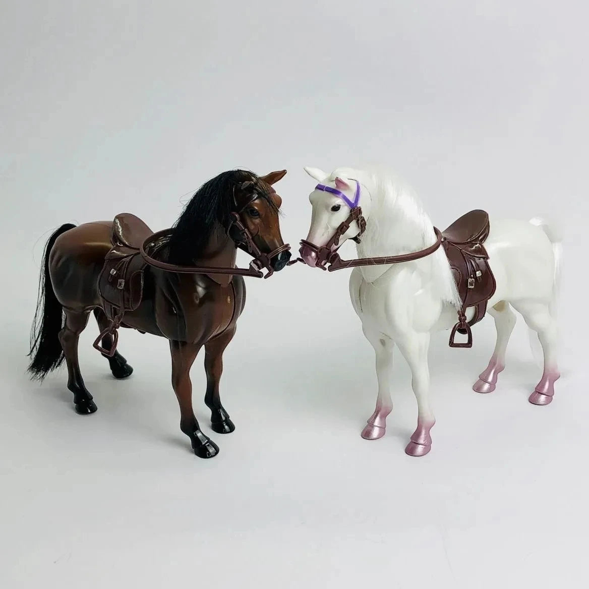 A pair of 1/12 scale dollhouse horse saddles and riding props, featuring a dark brown horse and a white horse.
