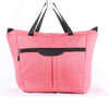 A pink fabric bag with black handles and a flap closure, used as a stroller accessory kit.
