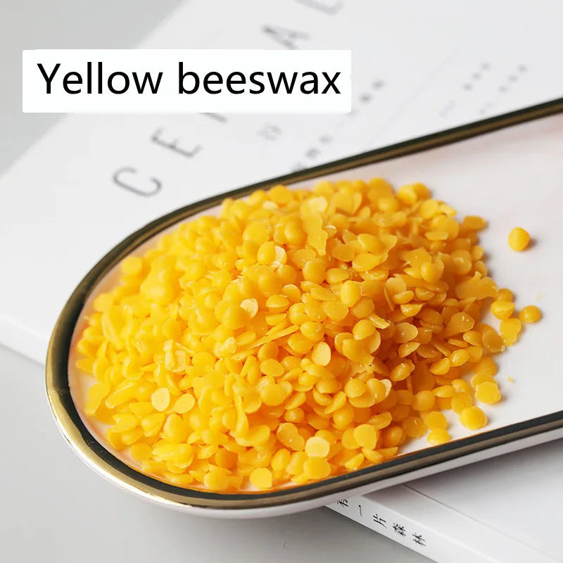 A close-up view of yellow beeswax pellets in a metal tray for DIY candle making and skincare.