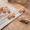 A collection of wooden and silicone car teether toys arranged on a light-colored mat on a wooden surface.