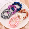 A collection of elegant pearl hair ties and bow scrunchies in various shades of blue, purple, silver, and pink arranged on a 
