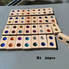 A rectangular arrangement of 32 wooden gemstone building blocks with acrylic crystals on a gray surface.