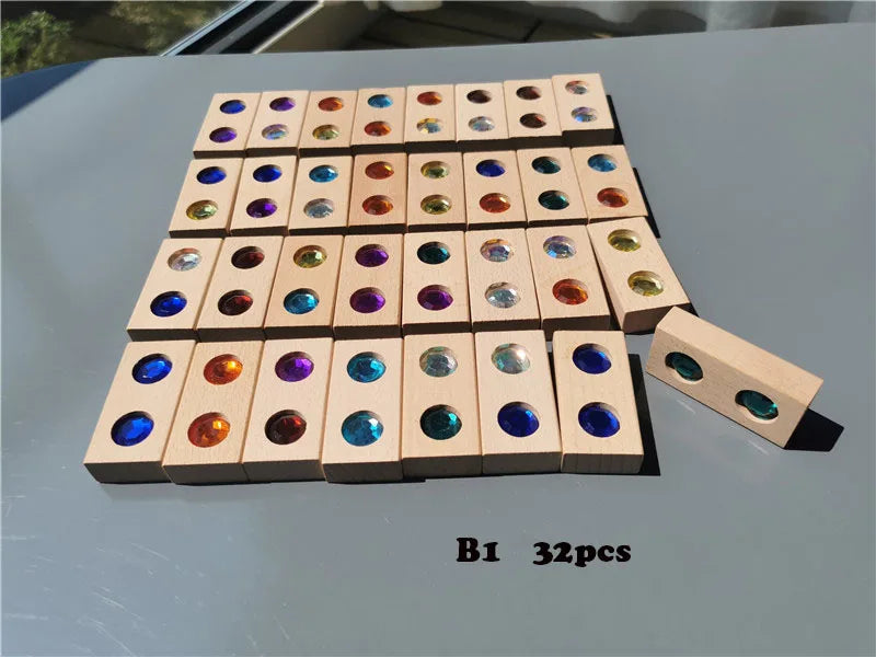 A rectangular arrangement of 32 wooden gemstone building blocks with acrylic crystals on a gray surface.