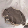 A black and beige striped kids cotton pullover sweatshirt hanging on a hanger.