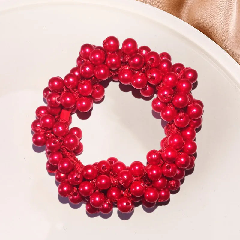 A circular arrangement of bright red pearl hair ties with bows, displayed on a white plate.