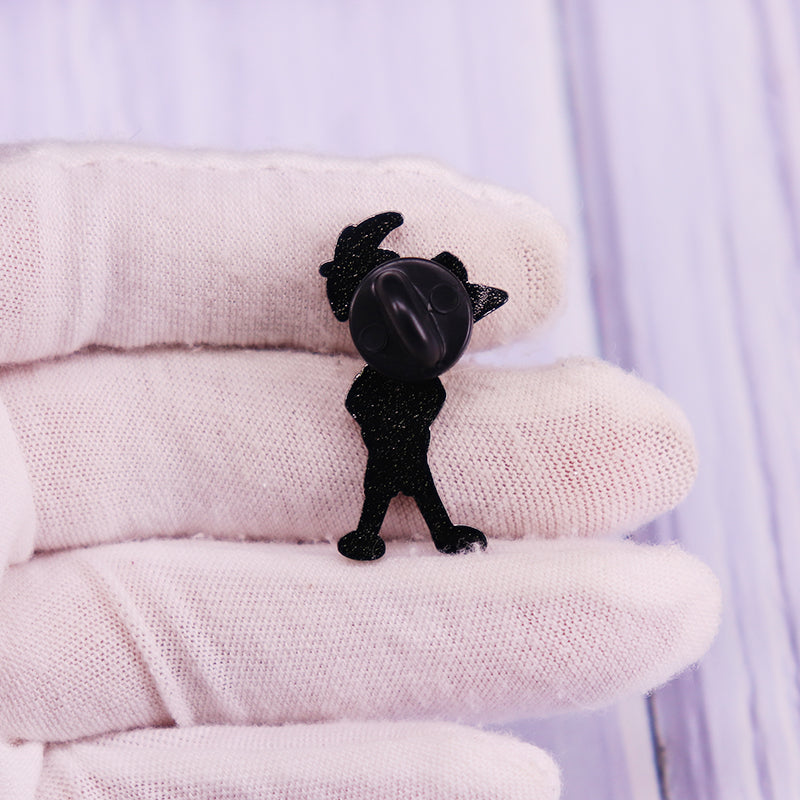 A black enamel pin shaped like a cartoon character dog is displayed on a white glove.