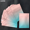 A stack of translucent pink and blue mini reusable ziplock bags are displayed on a dark surface.