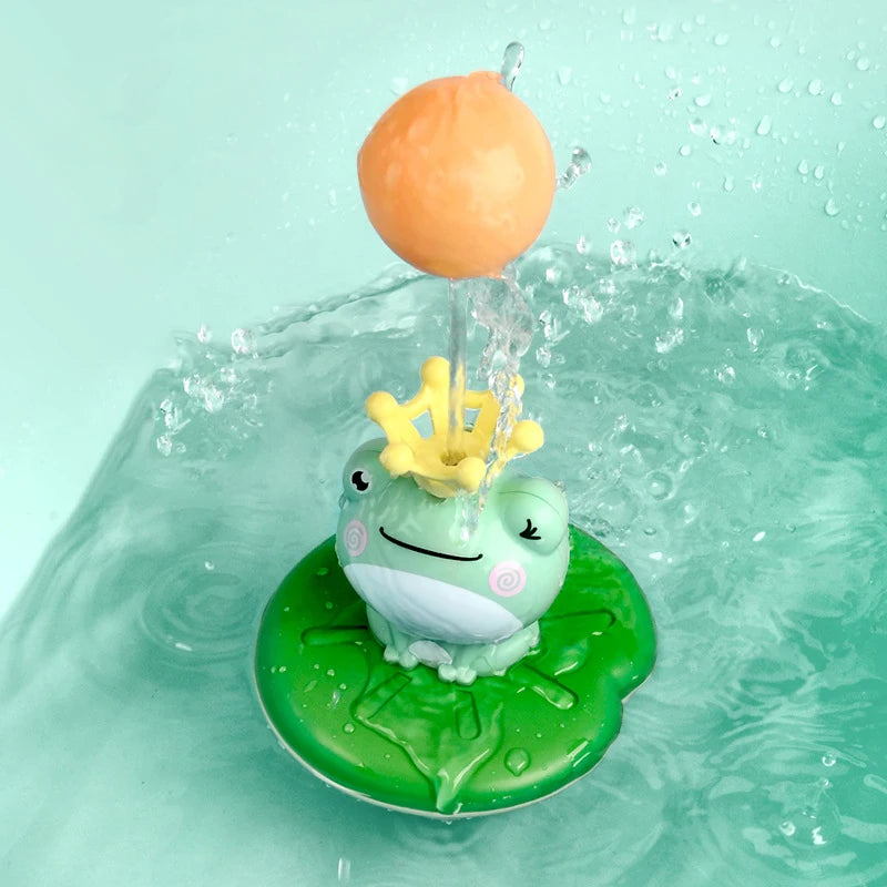 An orange sphere is being sprayed by a yellow crown from a green frog bath toy floating in water.