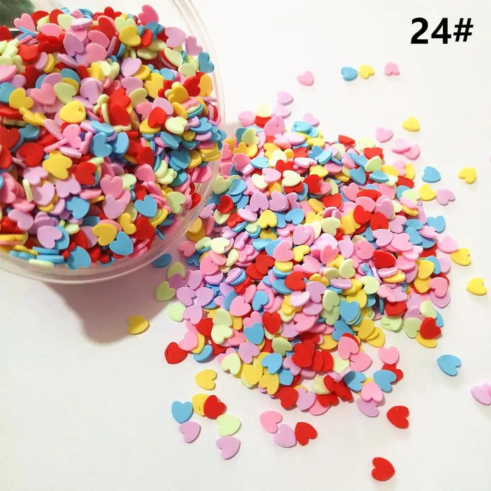 A pile of heart-shaped fake candy sprinkles in various colors like pink, red, yellow, and blue scattered on a white surface.