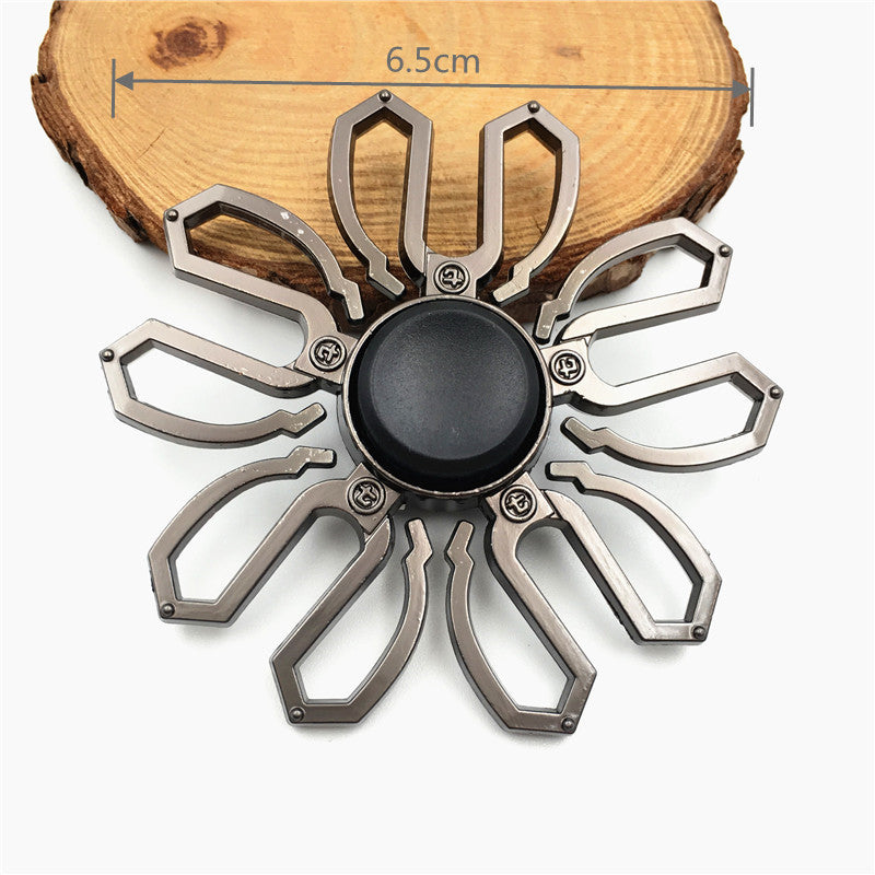 A metal fidget spinner with a rainbow finish is shown resting on a wooden surface.
