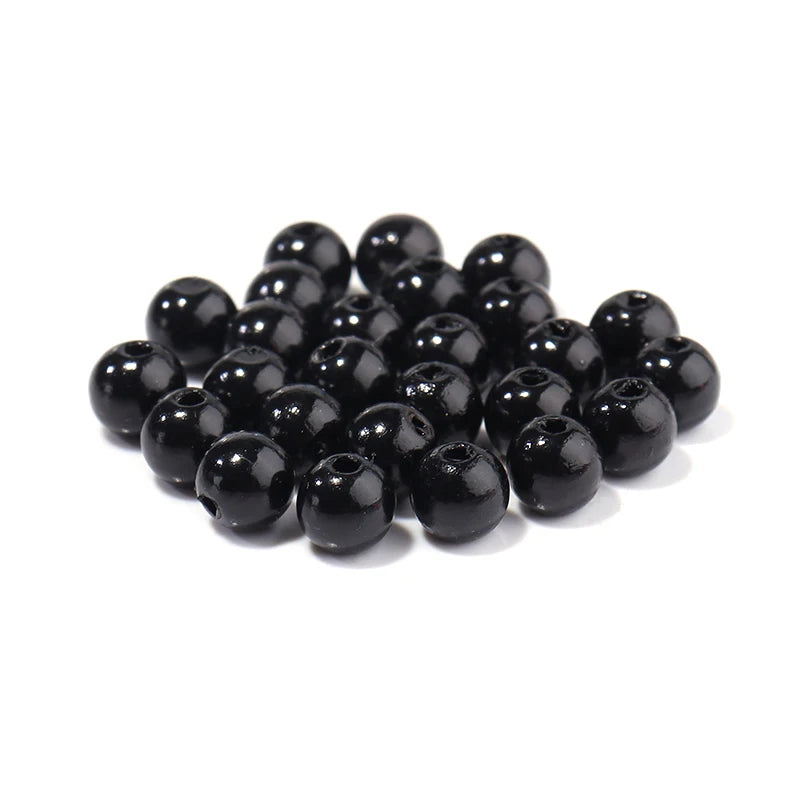 A pile of small, dark, spherical imitation pearl beads for DIY jewelry making.