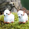 Two white miniature lamb figurines with pink accents resting on green moss.