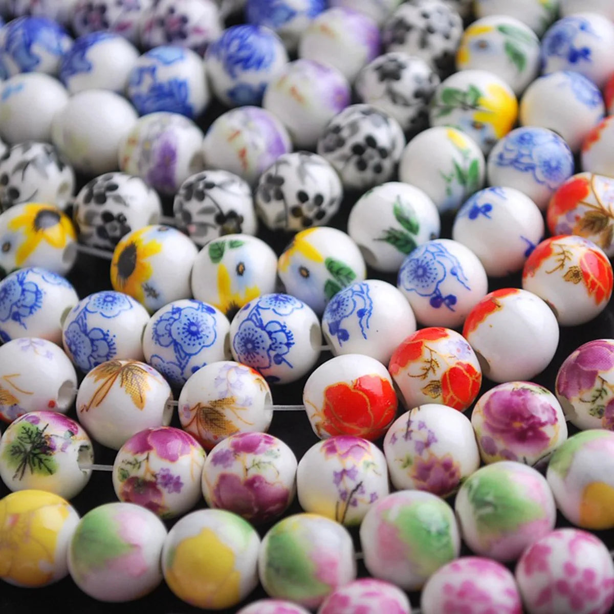 A collection of colorful floral ceramic beads in various shades of white, purple, and green for jewelry making.