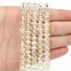A hand holds a strand of clear faceted crystal glass beads for jewelry making