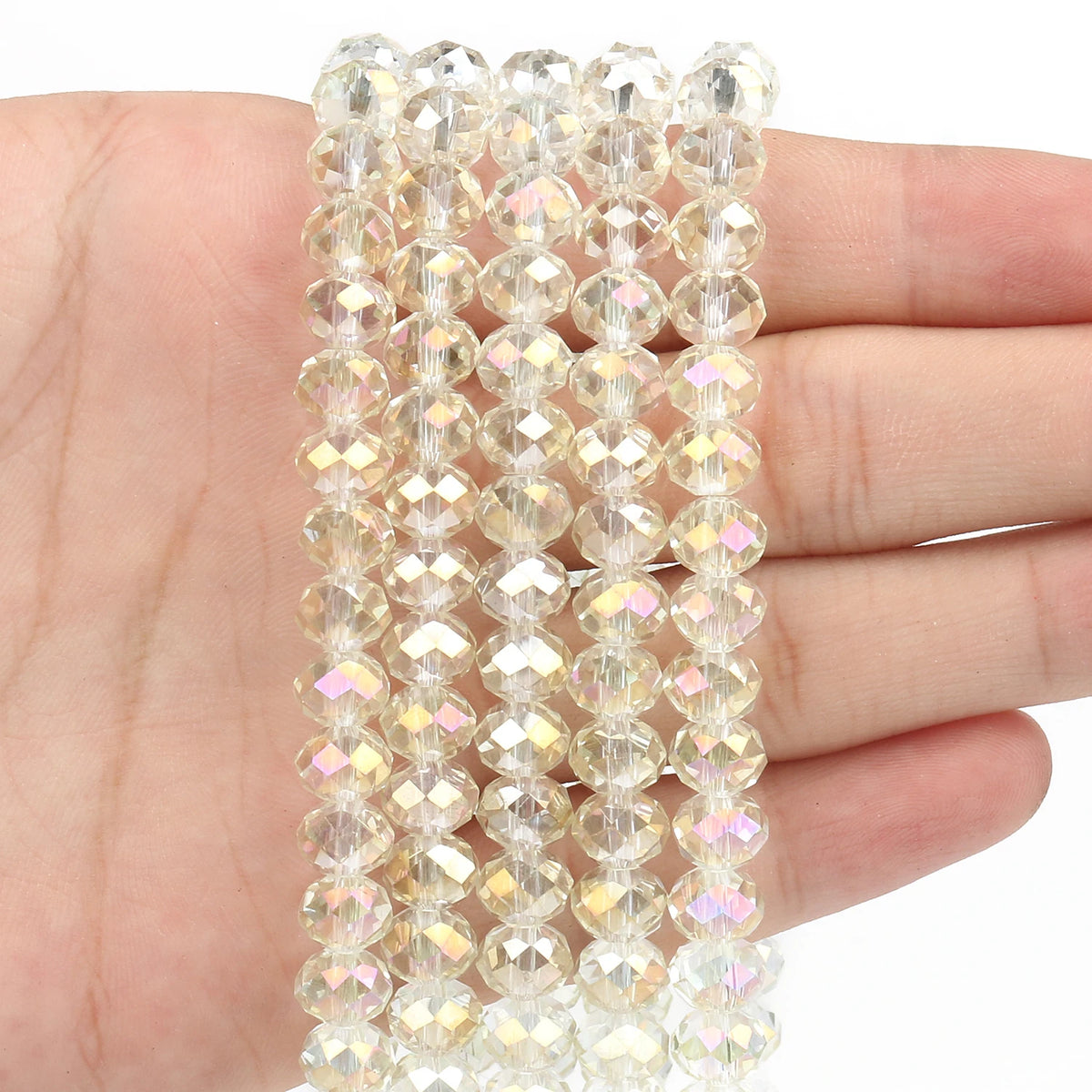 A hand holds a strand of clear faceted crystal glass beads for jewelry making