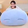 A light blue, oval-shaped plush toy pillow resembling a sleeping anime slime character with closed eyes and pink eyelashes.