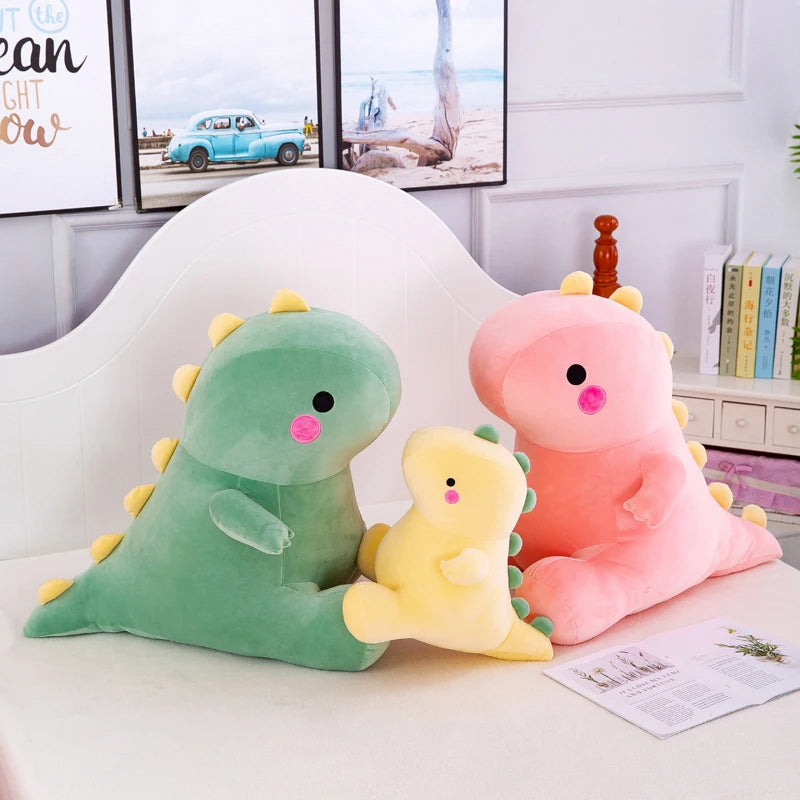 Two soft plush dinosaur toys, one green and one pink, sitting on a white table.