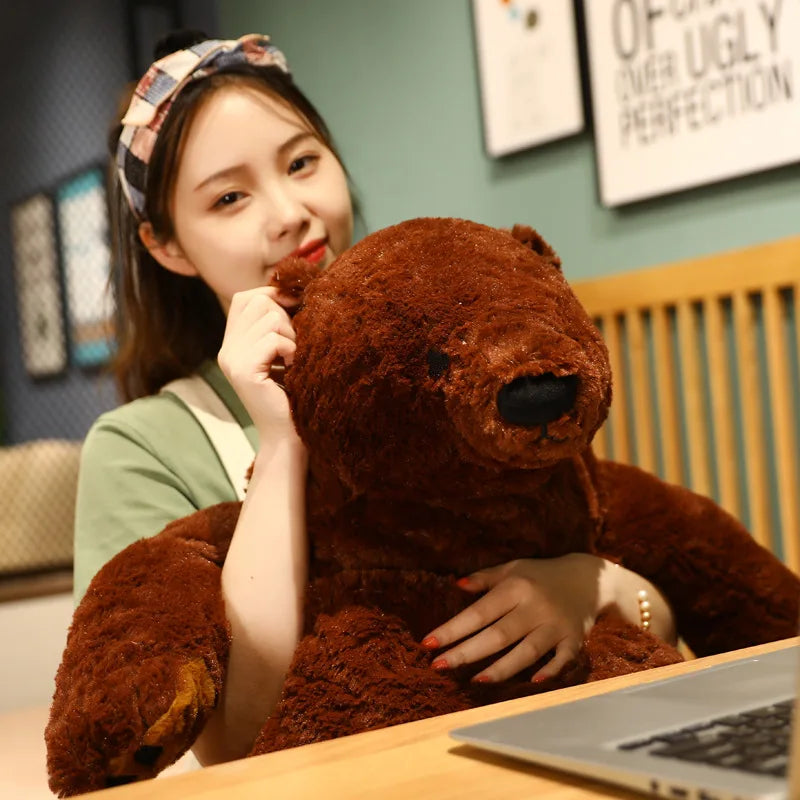 A woman is holding an oversized lifelike brown bear plush cushion in a close-up shot.