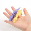 Two colorful rubber chicken fidget toys, purple and yellow, are held in a person's hand.
