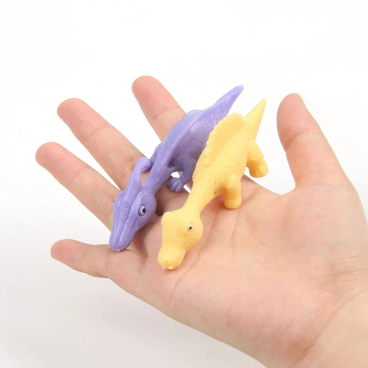 Two colorful rubber chicken fidget toys, purple and yellow, are held in a person's hand.