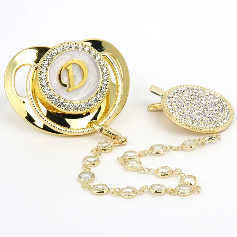 Gold and clear rhinestone pacifier featuring a personalized initial design and clip.