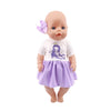A baby doll with light skin, pink hair, and a purple dress and bow.