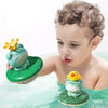 A baby is playing with a green frog bath toy that floats in water.