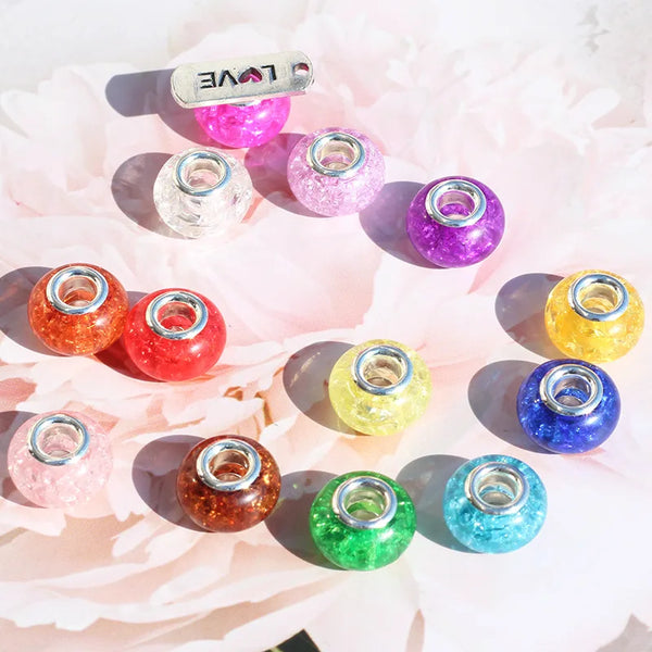 Perles intercalaires en résine colorées, nuances de rose, violet, or et bleu, disposées sur une épingle claire.