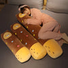 A woman is relaxing on a dark surface with several long, brown and yellow stuffed animal plush pillows.
