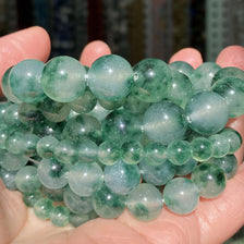 A handful of smooth, translucent green gemstone beads for jewelry making