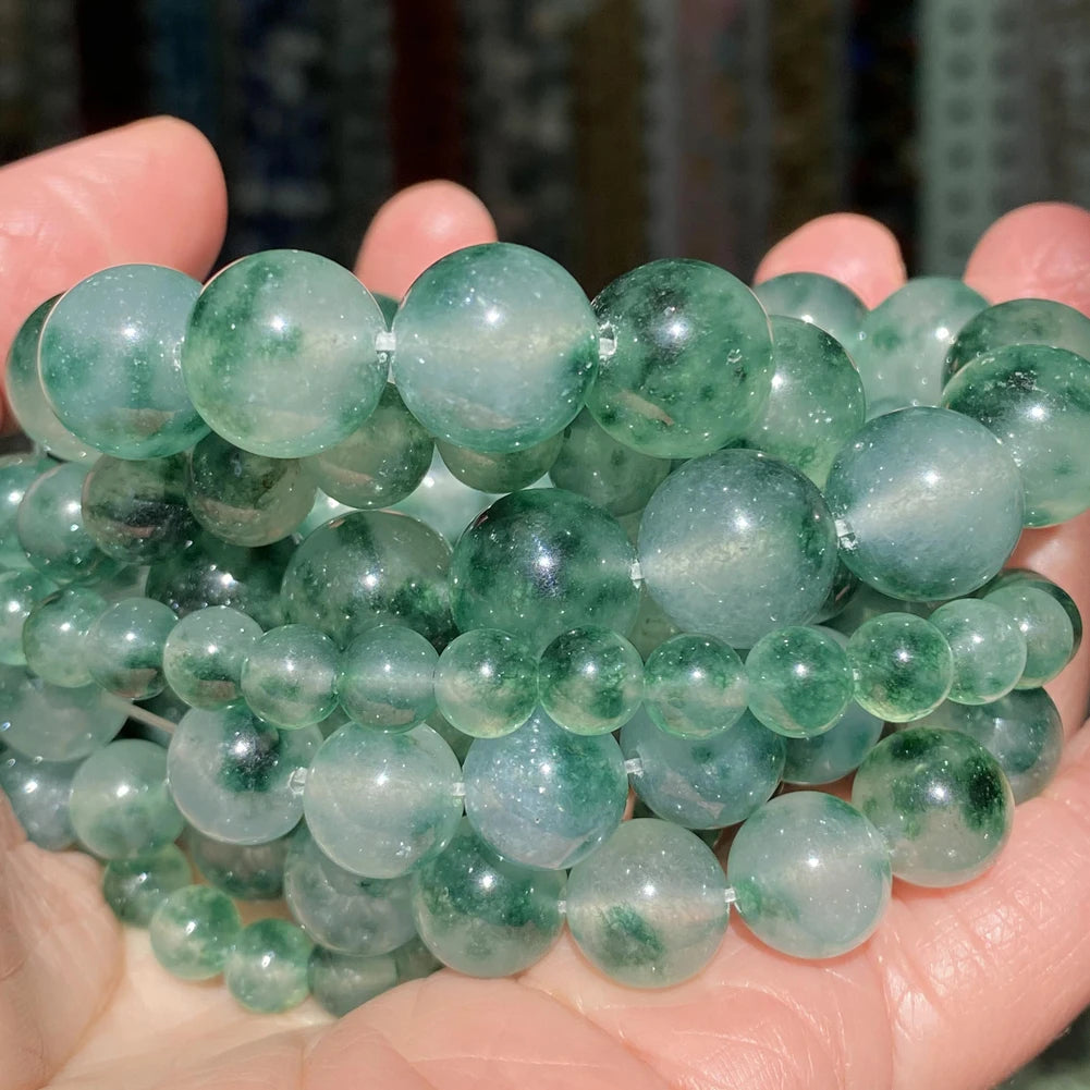 A handful of smooth, translucent green gemstone beads for jewelry making