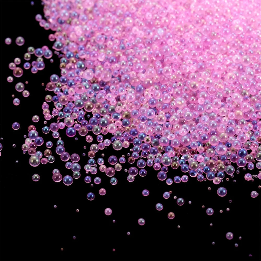 A pile of pink and purple mini glass bubble beads scattered against a black background.