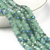 A strand of faceted, light green crystal glass beads for jewelry making is displayed in a white bowl.