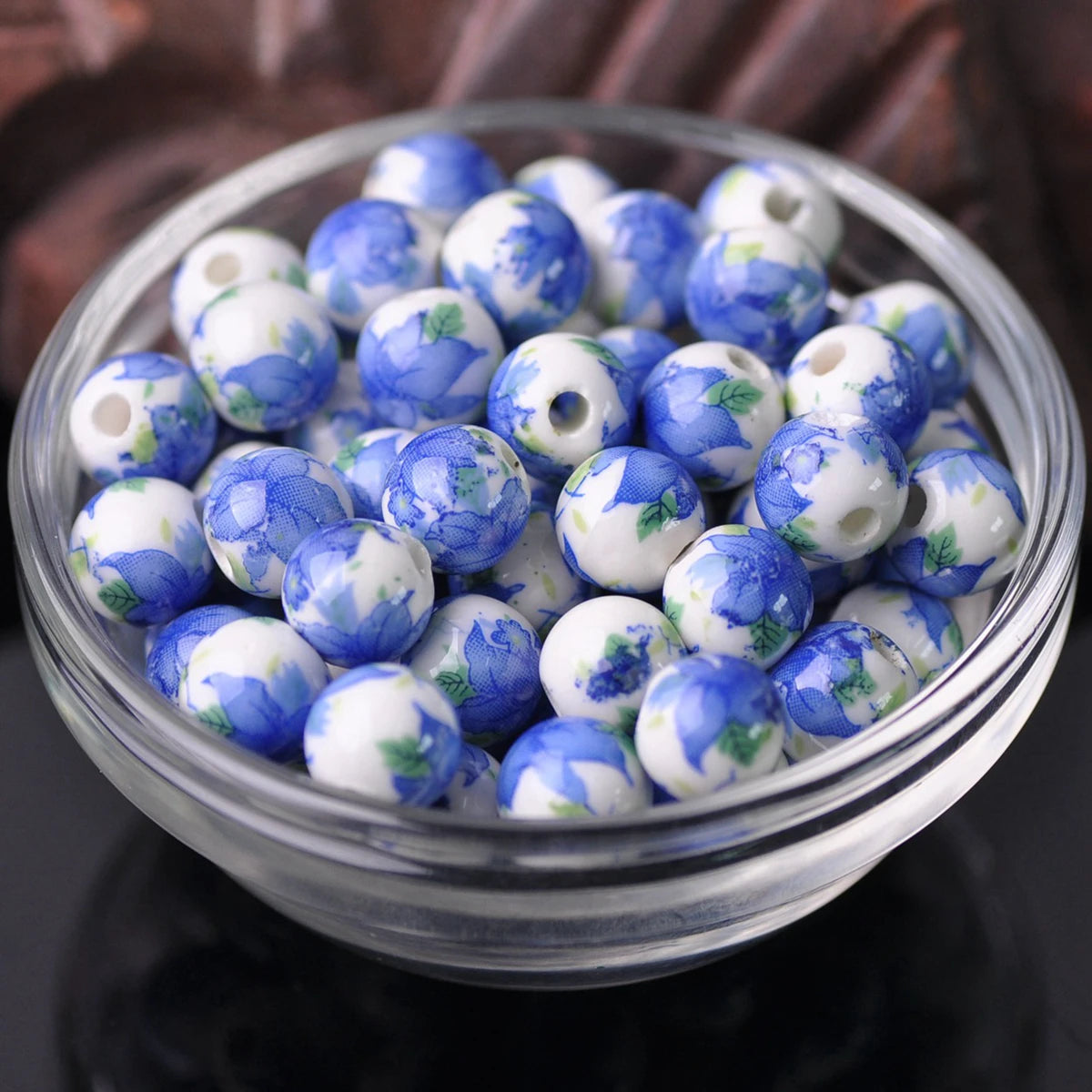 A bowl filled with blue and white floral ceramic beads for jewelry making