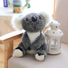 A gray koala plush toy with white fur and black accents sitting next to a white decorative lantern.