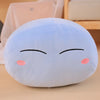 A light blue, round plush toy pillow shaped like a character with closed eyes and pink cheeks.