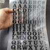 A sheet of DIY iron-on heat transfer patches showing various uppercase and lowercase letters and symbols.