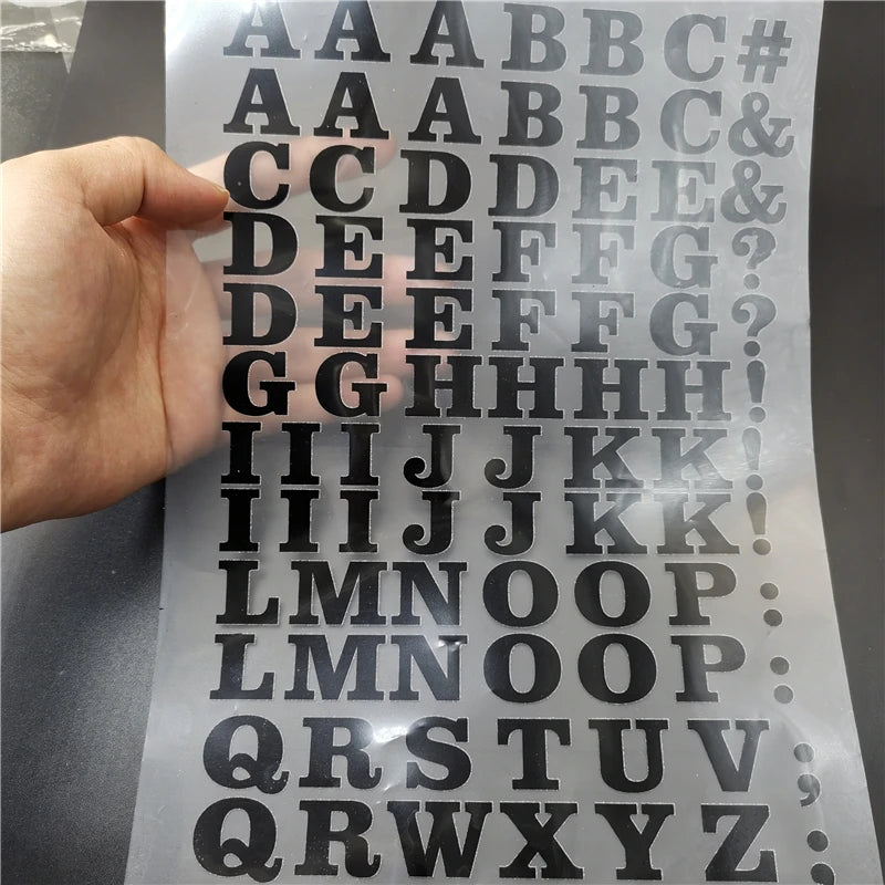 A sheet of DIY iron-on heat transfer patches showing various uppercase and lowercase letters and symbols.