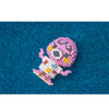 A pink and white Lego-style figure resembling a creature is placed on a blue, granular surface.