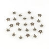 A collection of small, silver-toned Tibetan style hollow flower bead caps for jewelry making.