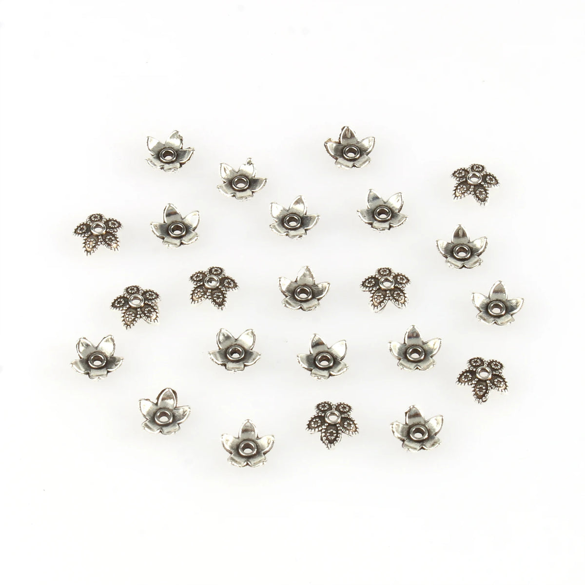 A collection of small, silver-toned Tibetan style hollow flower bead caps for jewelry making.