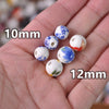 A hand holds various sizes of white ceramic beads with floral designs, including 10mm and 12mm options.
