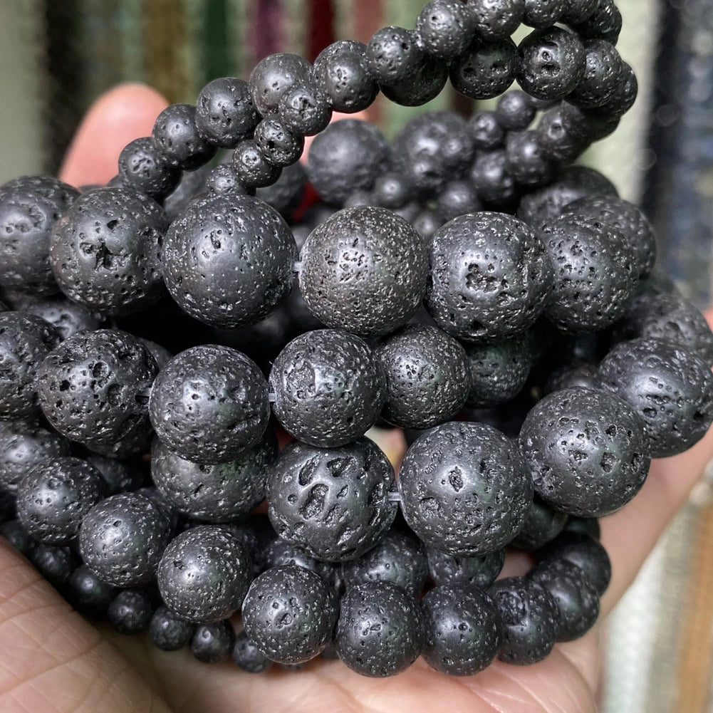 A close-up of dark gray natural gemstone beads for jewelry making, featuring various textures and sizes.