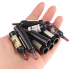 A hand holds a set of miniature resin wine bottles for dollhouse decor.