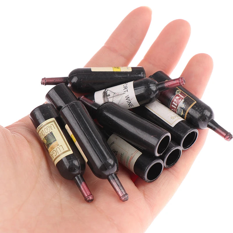 A hand holds a set of miniature resin wine bottles for dollhouse decor.