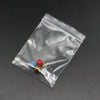 A clear resealable plastic bag contains several small, colorful glass or plastic beads and items.