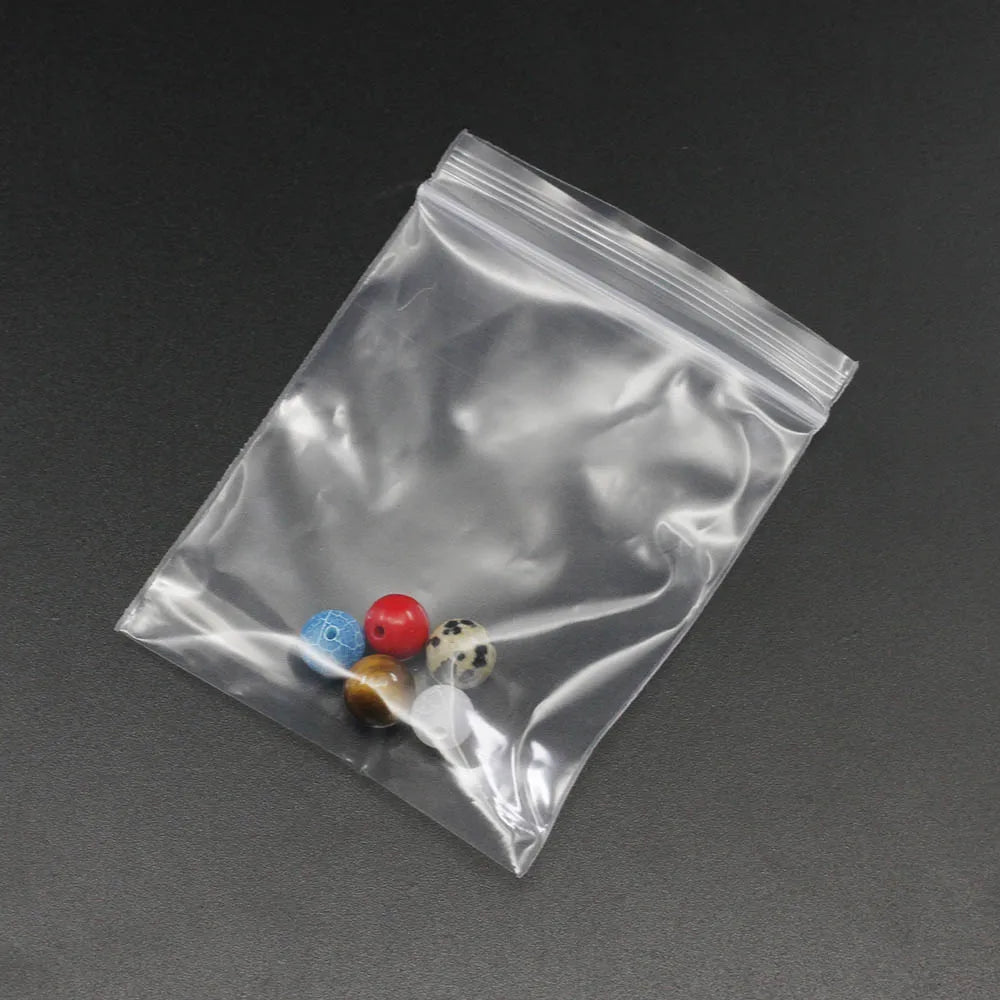 A clear resealable plastic bag contains several small, colorful glass or plastic beads and items.