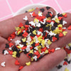 A hand holds a pile of colorful polymer clay slices in red, yellow, white, and black for crafting projects.