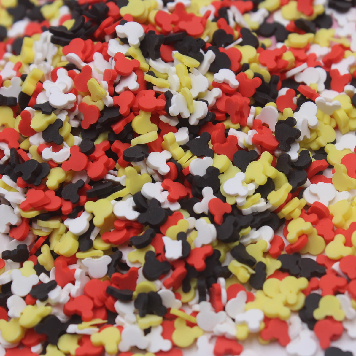 A close-up view of colorful cartoon polymer clay slices in red, yellow, white, and black mixed together.